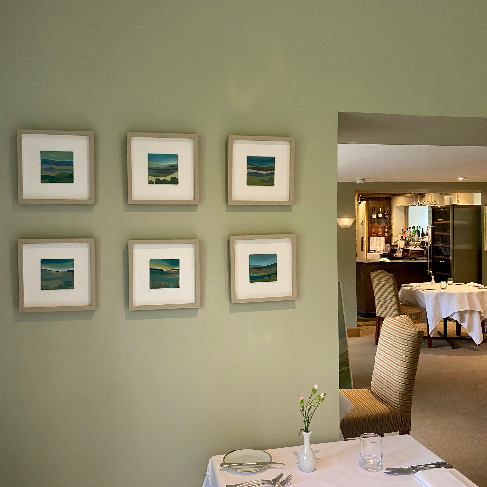 Framed artwork on a wall with a hotel dining area in the background