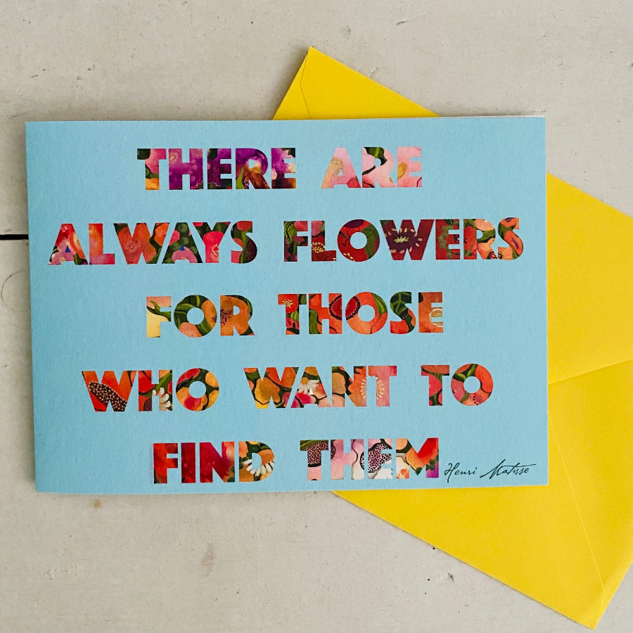 A square light blue greeting card with a floral quote by Henri Bréguet, placed on top of a bright yellow envelope against a light beige textured background.