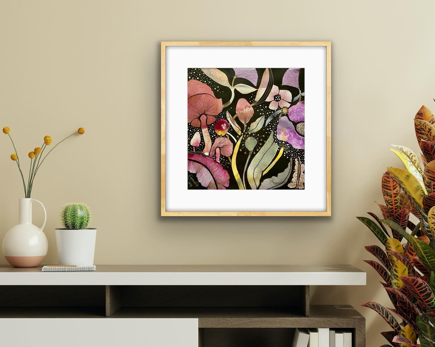 Framed autumnal floral artwork on a wall with decorative plants, mushrooms, fungi and a shelf below.