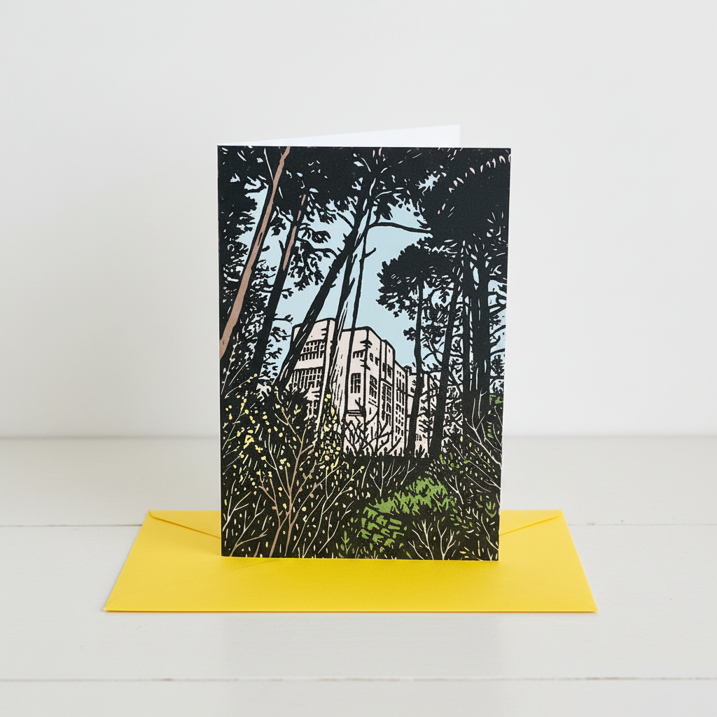 A vertical art print or card featuring a black-and-white linocut-style illustration of a building surrounded by dense trees and foliage, with a bright yellow envelope placed underneath on a white surface against a white background.