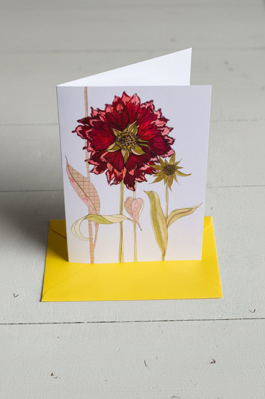 A botanical art print featuring a large deep red dahlia and a smaller yellow flower with green leaves, presented on a white sheet with a bright yellow border, set against a light gray textured background.