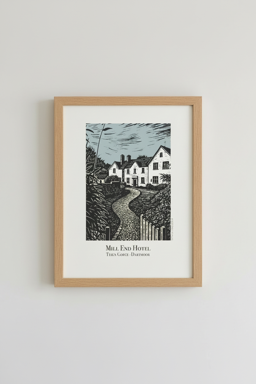 A framed art print featuring a black and white block print of Mill End Hotel with a light wood frame and white mat, mounted on a neutral light grey wall.