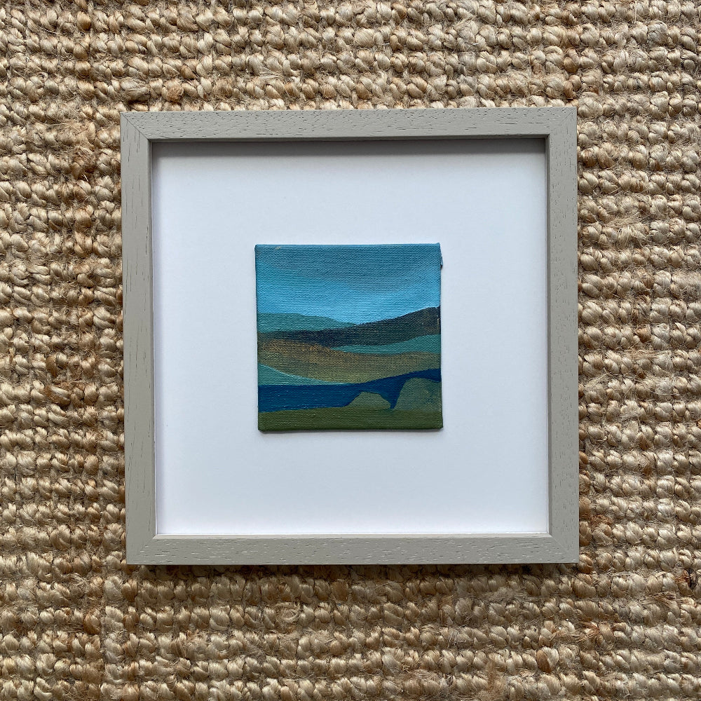 Framed artwork of an abstract  landscape on a textured beige wall