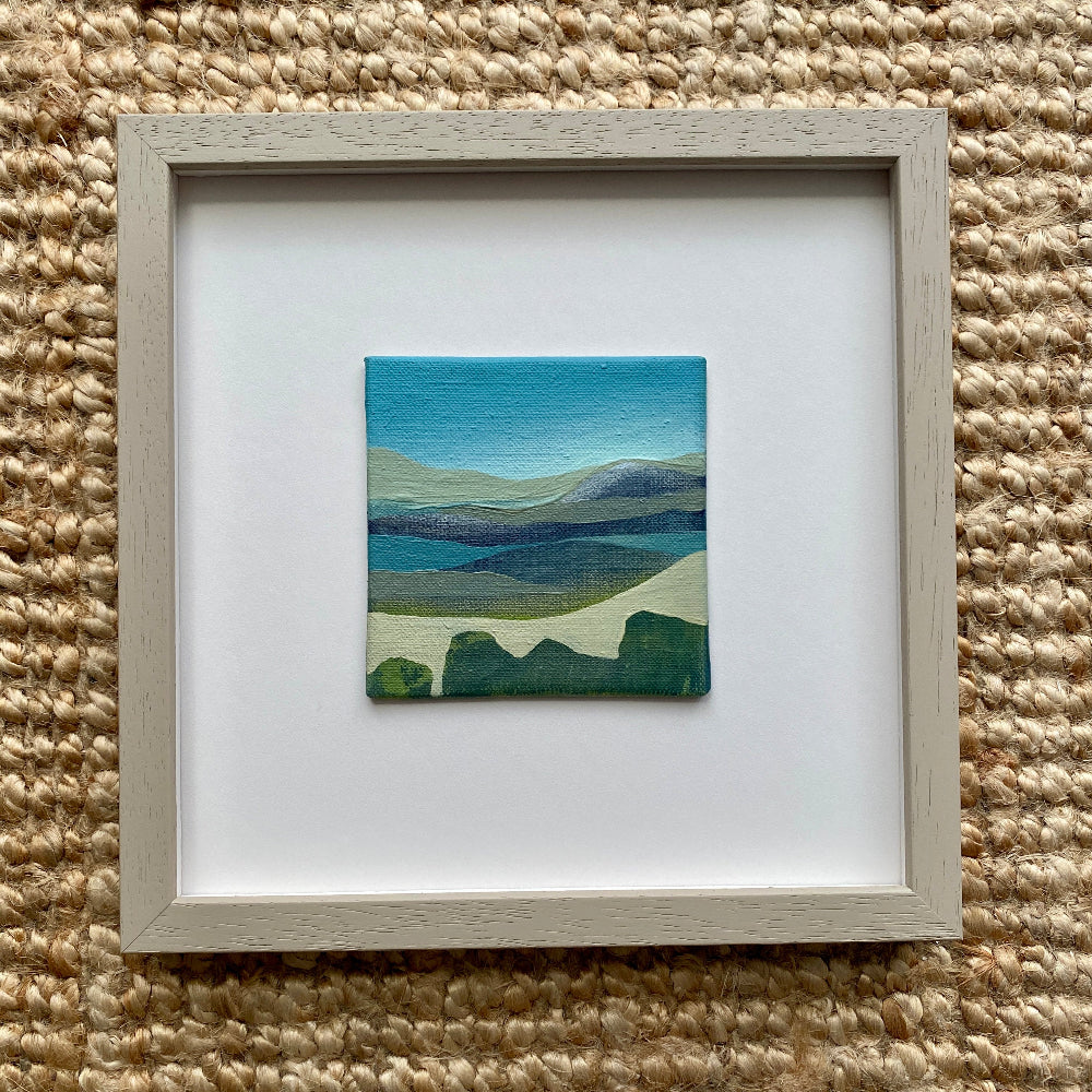 Framed artwork of a landscape on a textured beige surface