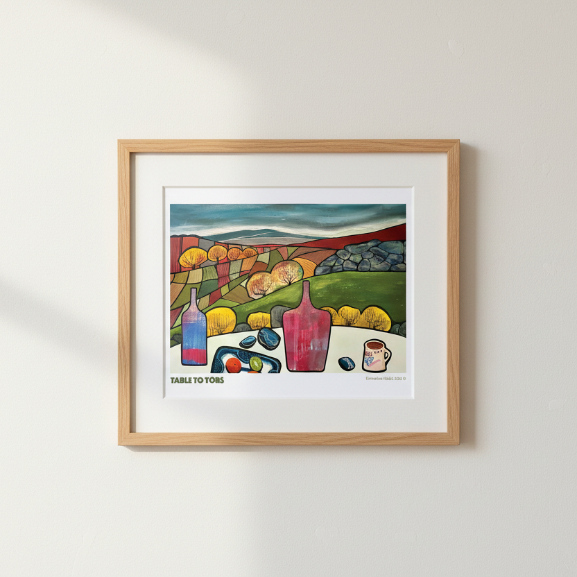A framed art print titled 'TABLE TO TORS' featuring a colorful still life illustration of lemons, bottles, and fruit on a table, displayed on a light beige wall.