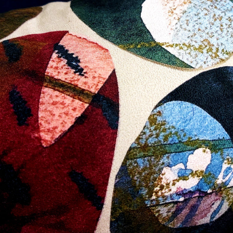Close-up of a textured abstract rug with organic shapes in deep red, pink, cream, green, blue, black, and gold flecks.