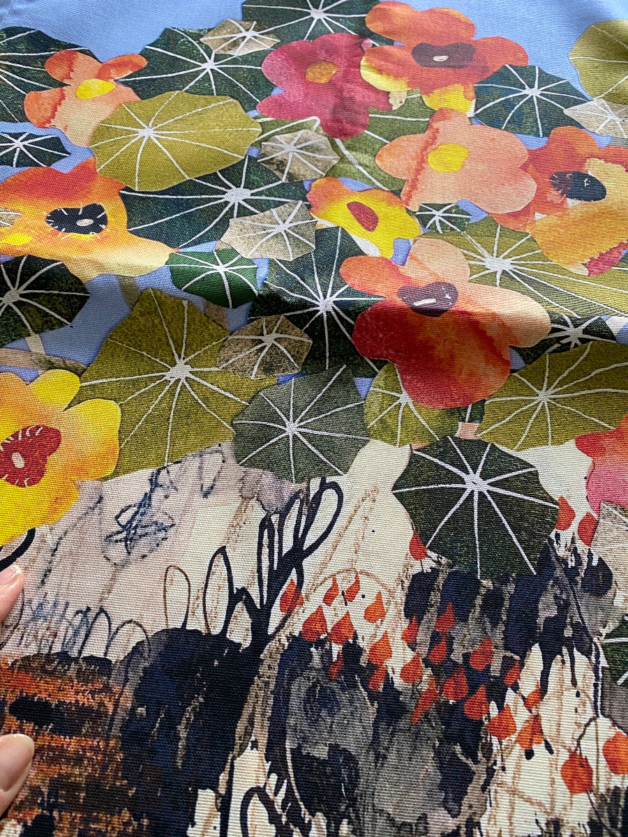 A close-up of a fabric or wallpaper pattern featuring large watercolor-style flowers in red, yellow, orange, and pink over a dark green and blue background, with abstract black brushstrokes and white starburst motifs.
